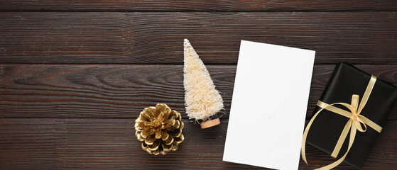 Beautiful Christmas composition with blank card, gift box and decor on dark wooden background with space for text