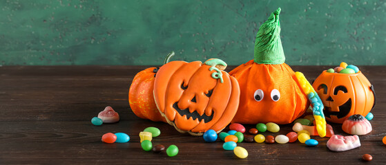 Paper pumpkins for Halloween and tasty sweets on wooden table. Banner for design
