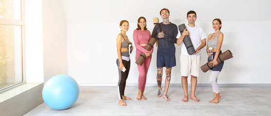 Group of young people with yoga mats in gym