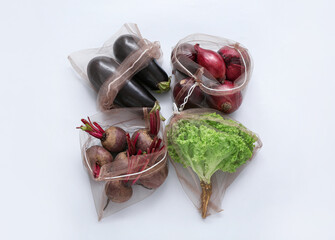 Eco bags with different fresh vegetables on light background