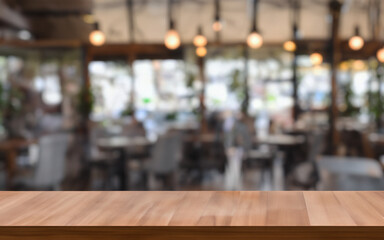 Photo of empty wooden table, where you can add your cup of coffee or some decoration. Focus on the table and blur on the background. 