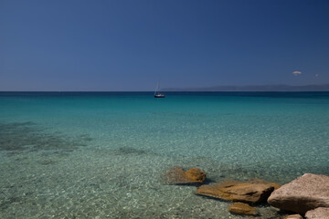 a sailboat in the middle of the ocean with mountains in the background and a blue sky with clouds, panoramic view, magic realism