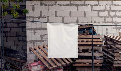 Blank vinyl poster with space for mockup hanging on construction site fence with construction waste