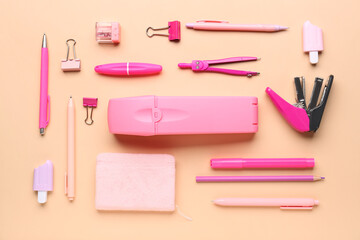 Pink pencil case with school stationery on beige background