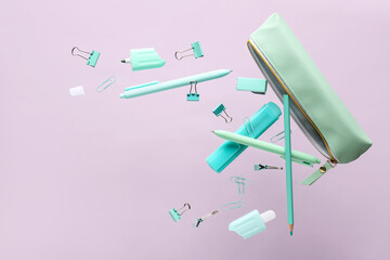 Flying pencil case and school stationery on purple background