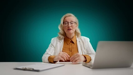 Middle aged anchorwoman presenting latest news against empty green background
