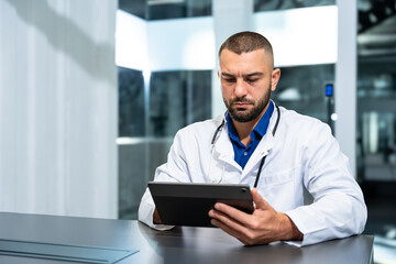 Handsome male doctor with tablet computer gadget consultating patient online