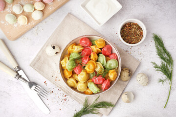 Bowl of boiled colorful dumplings with dill and quail eggs on white background