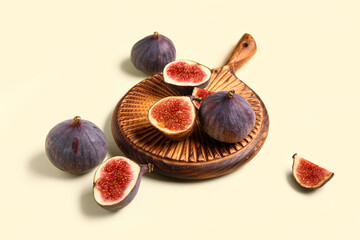 Wooden board with fresh ripe figs on yellow background