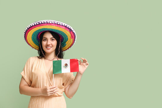 Beautiful Mexican woman in sombrero and with flag on green background