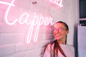 Happy young woman standing near illuminating inscription