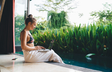 Focused woman working on laptop in tropical resort