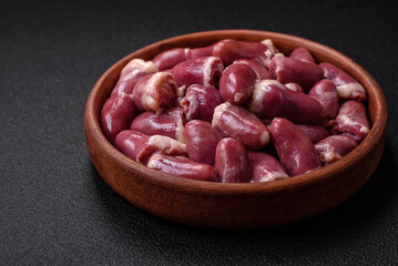 Fresh raw chicken, turkey or duck hearts on a ceramic plate with salt and spices