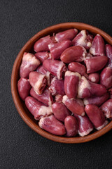 Fresh raw chicken, turkey or duck hearts on a ceramic plate with salt and spices