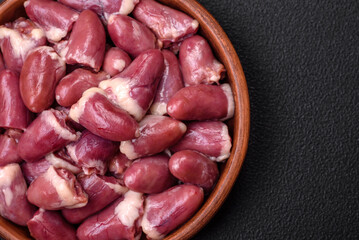 Fresh raw chicken, turkey or duck hearts on a ceramic plate with salt and spices