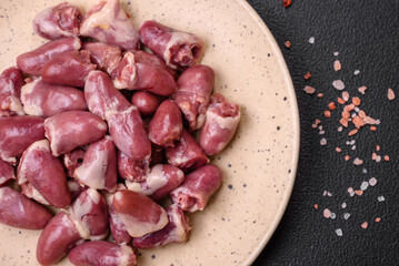 Fresh raw chicken, turkey or duck hearts on a ceramic plate with salt and spices