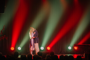 Professional couple dancing in spotlights smoke on stage. Beautiful young woman and man on floodlights background. Emotional duet performing choreographic art.