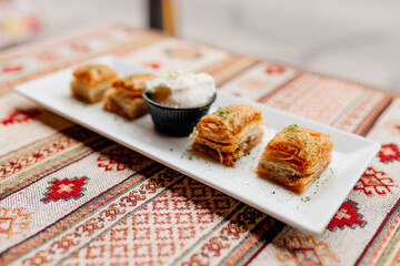 Turkish sweets on Turkish white and red napkins. Dessert close-up. Delicious pastries on the table. Baklava on a white plate