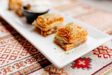 Turkish sweets on Turkish white and red napkins. Dessert close-up. Delicious pastries on the table. Baklava on a white plate