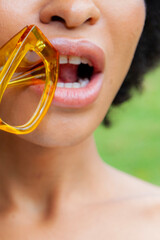 Woman biting sunglass mouth close up