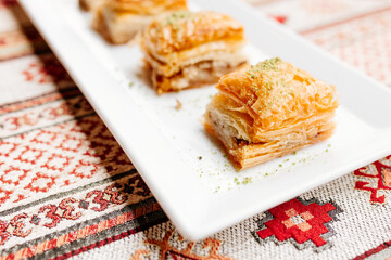 Turkish sweets on Turkish white and red napkins. Dessert close-up. Delicious pastries on the table. Baklava on a white plate