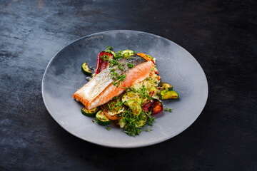 Traditional Mediterranean salmon fish fillet with vegetable cuscus served as close-up on a design bowl with copy space - obrazy, fototapety, plakaty