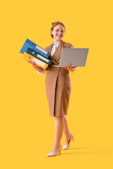 Young businesswoman with document folders and laptop on yellow background