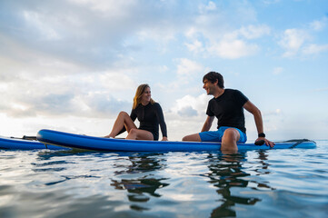 Obraz premium Young man and young woman enjoying a day of paddlesurfing