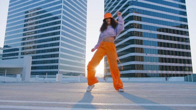 Funny girl performing cool dance at glass office buildings background. Concept of hip hop and break dance performance for music video. Youth subculture contemporary choreography cinematic RED camera
