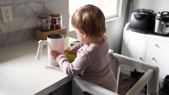 Toddler playing in the kitchen with household objects