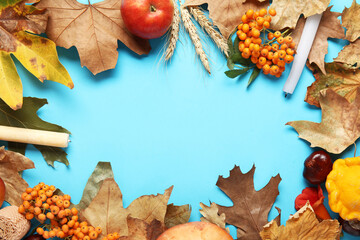 Naklejka na ściany i meble Frame made of autumn leaves with candles, rowan and ears of wheat on blue background