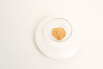 Dry crushed garlic in a glass plate on a white background.
