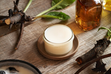 Homemade comfrey root ointment in a glass jar on a table