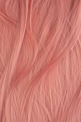 Beautifully laid light pink wavy shiny curls close-up as a background