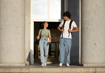 Happy classmates wearing casual clothes leaving college. They are walking down the stairs of the...