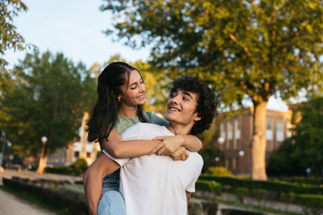 Naklejka premium Pair of cute students leaving college. The girl is standing on top of the boy and they are looking at each other and smiling