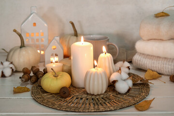 Composition with burning candles and beautiful autumn decor on light wooden table