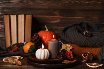 Beautiful autumn composition with candles, pumpkins and books on brown wooden background