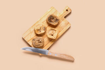 Wooden board with sweet dried figs on orange background