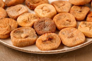Plate with sweet dried figs on brown background, closeup