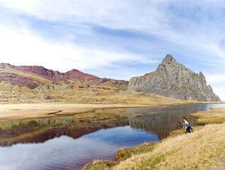 young girl taking pictures in a mountain lake. in the french pyrenees. with tripod and cell phone.