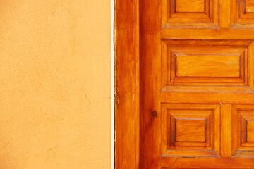 Closeup of part wooden entrance door and yellow wall. Part of renovated door with pattern