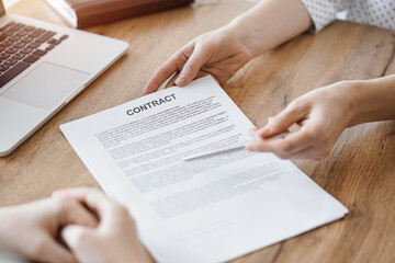 Obraz premium Businesswoman lawyer pointing into contract special points admitting something for colleague or client at the wooden desk in office. Business people teamwork and partnership, meeting concept