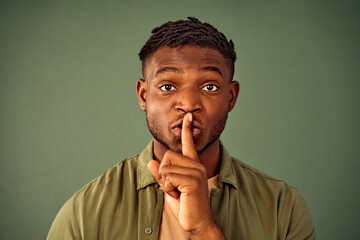 Keep my secret. Portrait of serious young man with afro hairstyle doing shush gesture near lips...