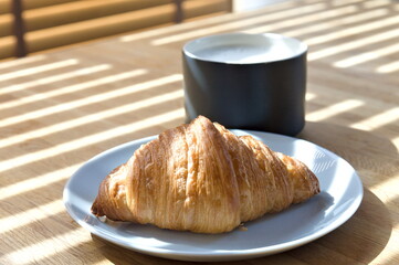 breakfast view of croissant and a cup of coffee