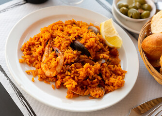 Appetizing racy seafood paella with mussels, prawns and slice of fresh lemon.Traditional Valencian cuisine