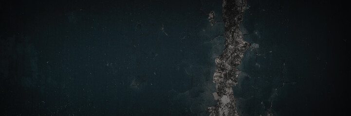 Dark wide panoramic background. Peeling paint on a concrete wall. Dark grunge texture of old cracked flaking paint. Weathered rough painted surface. Patterns of cracks. Darkness background for design.