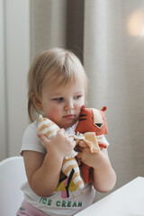 Little baby girl playing with funny small tiger toy, symbol of new 2022 in a sunny nursery