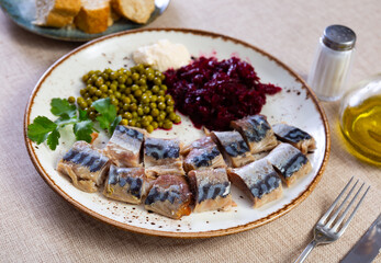 Cold smoked mackerel with grated beetroot and green peas served in a plate with other table appointments