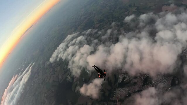 Aerial Acrobatics: Skydiver Executes Head Down Move Over Clouds, sunset